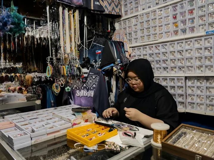 Pemilik kedai sedang menyusun barang di kaunter