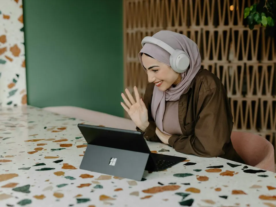Seorang wanita sedang video call dan melambai